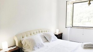 Una camera da letto con un letto, comodini, una finestra e un lampadario.