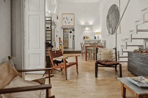 Ein geräumiges Wohnzimmer mit Holzboden, einem Essbereich mit Tisch und Stühlen sowie einer Küche im Hintergrund.