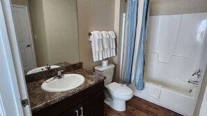 Ein Badezimmer mit Waschtisch, Spüle, Spiegel, Toilette und Badewanne.