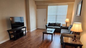 Ein Wohnzimmer mit Flachbildfernseher, zwei Sofas, einem Couchtisch und einer Lampe.