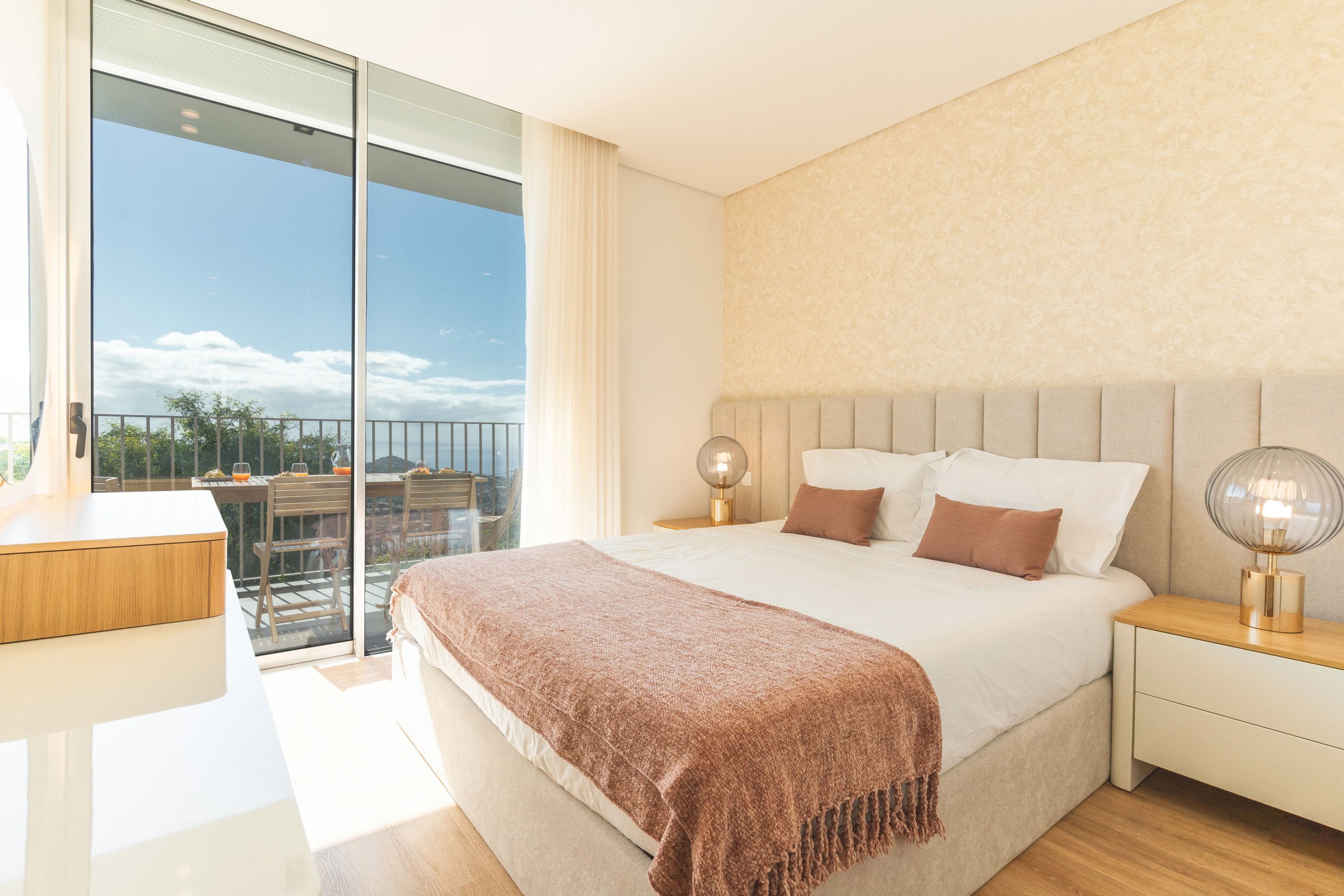 Un dormitorio moderno con una cama grande, lámparas de noche, una mesita de noche y vistas al exterior.