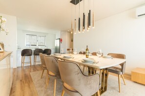 A modern dining area with a long table, multiple chairs, and hanging pendant lights. - Sunny Stay Atlantic Gardens by Atlantic Holiday (Camara de Lobos)