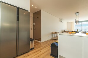 A modern kitchen with stainless steel appliances, a wooden floor, and a view of the city. - Sunny Stay Atlantic Gardens by Atlantic Holiday (Camara de Lobos)