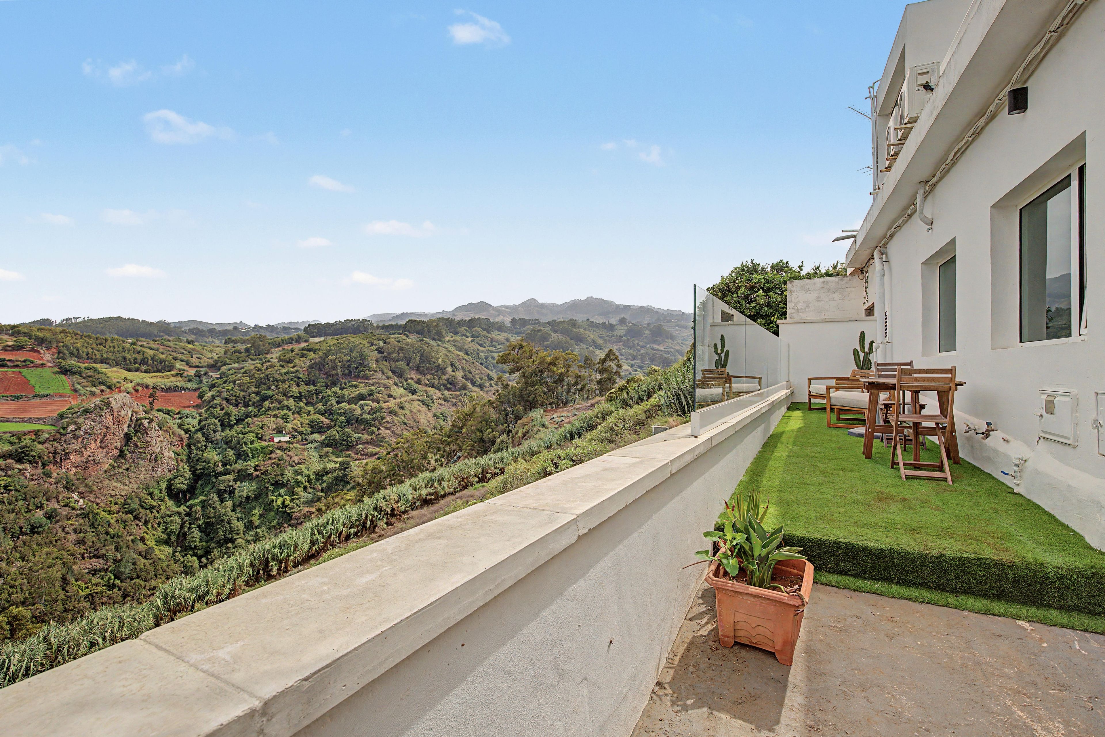 Un balcón con vista a un paisaje verde y colinas lejanas.