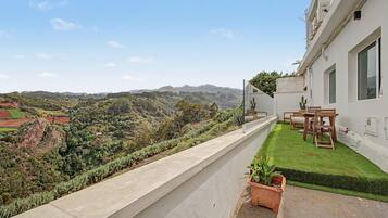 Un balcón con vista a un paisaje verde y colinas lejanas.