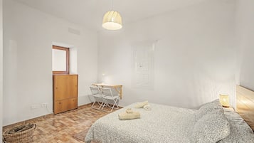 Un dormitorio con una cama, un escritorio con silla, una lámpara colgante y una puerta.
