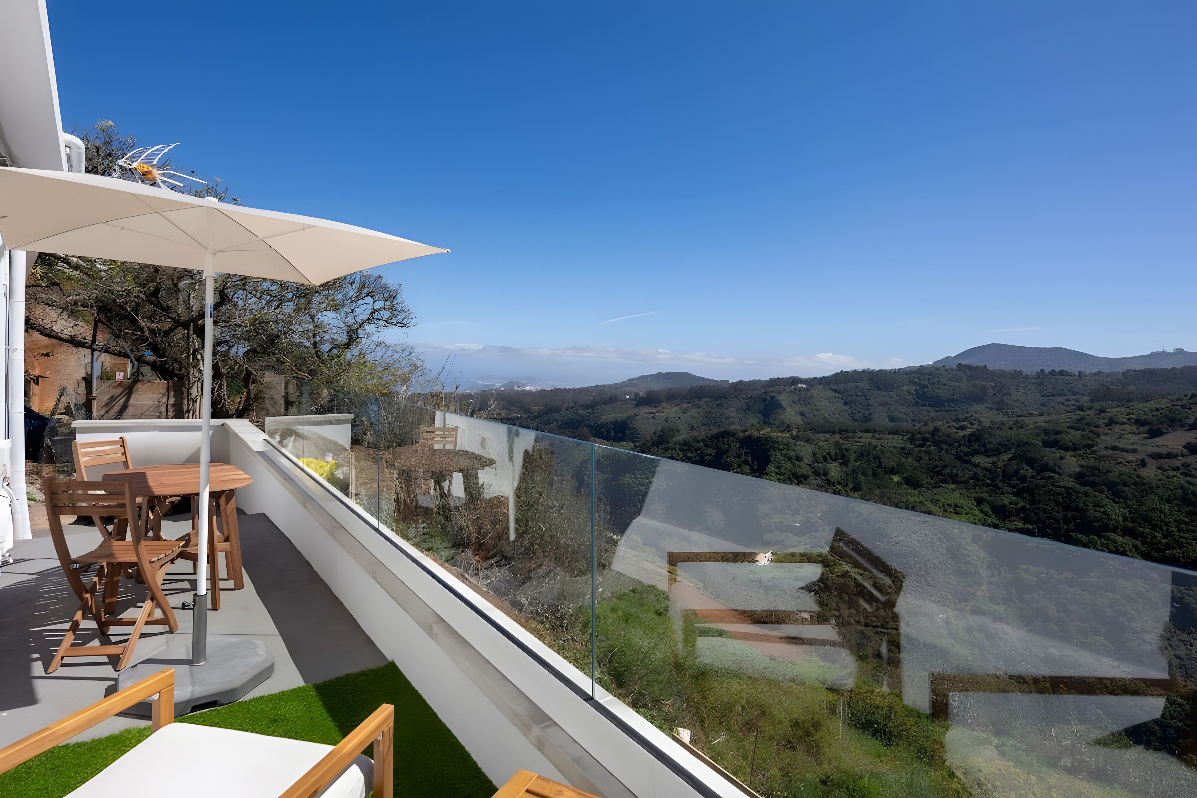 Un balcon avec une table et des chaises, donnant sur un paysage montagneux.