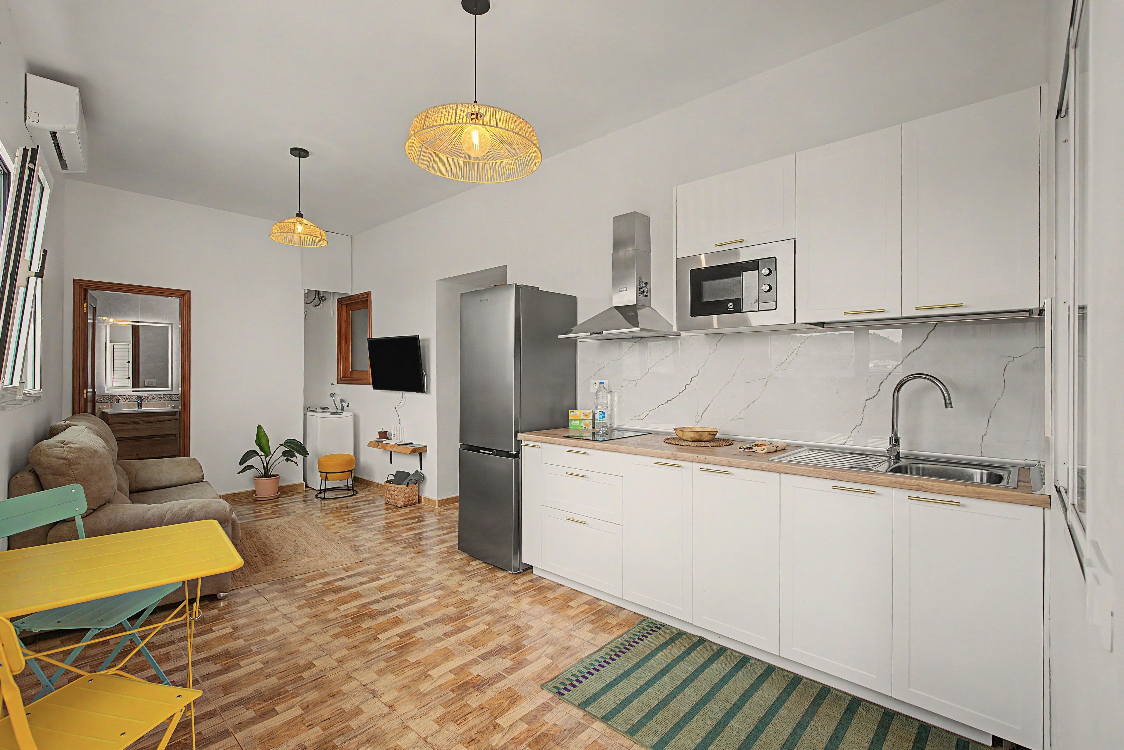 A compact kitchen with a built-in microwave, a stainless steel refrigerator, and a wooden countertop.