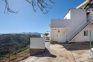 Ein Gebäude mit einer Treppe, einer Tür mit einem roten Schild und Blick auf eine gebirgige Landschaft.