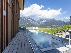 A wooden deck with a pool, lounge chairs, and a mountain view. - One-bedroom Cabin (Haus)