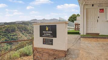 Propiedad rural llamada 'FINCA RURAL - EL PERAL' con un letrero, una puerta y vistas del paisaje circundante.
