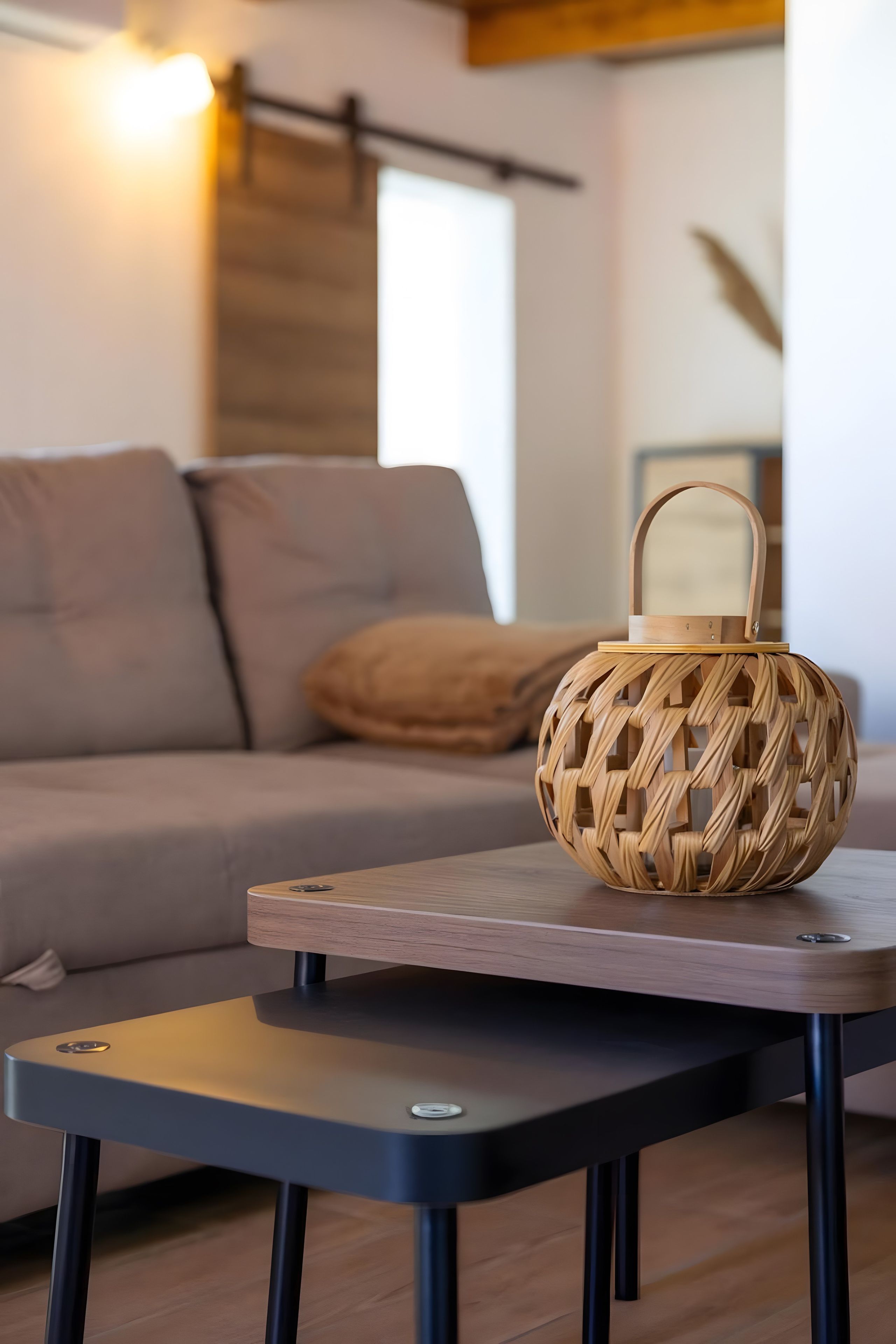 Un salon moderne avec un canapé, un panier en osier posé sur une table et une lampe.
