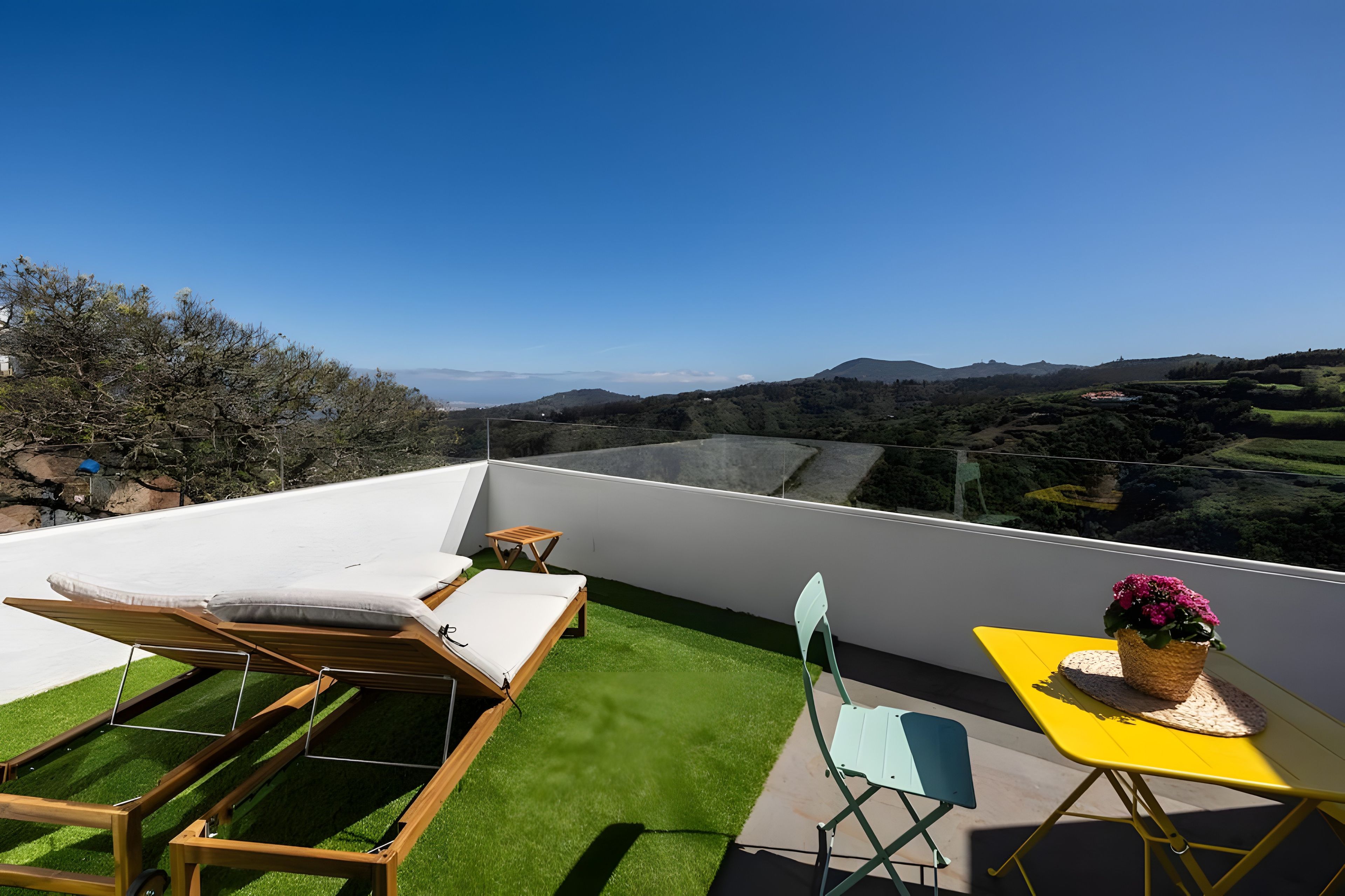Une terrasse sur le toit offrant une vue dégagée sur le paysage, notamment sur les collines et une étendue d’eau.