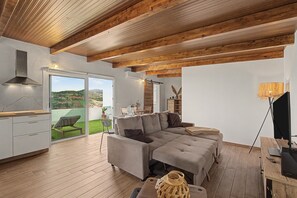 A modern living space with a wooden ceiling, a grey sofa, a dining area, and a view of the outdoors. - Penthouse with a view (Las Palmas)