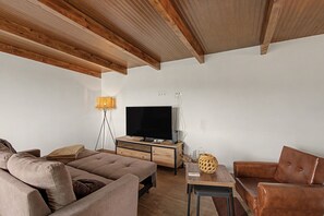 A living room with a sofa, a coffee table, a television, and a lamp.