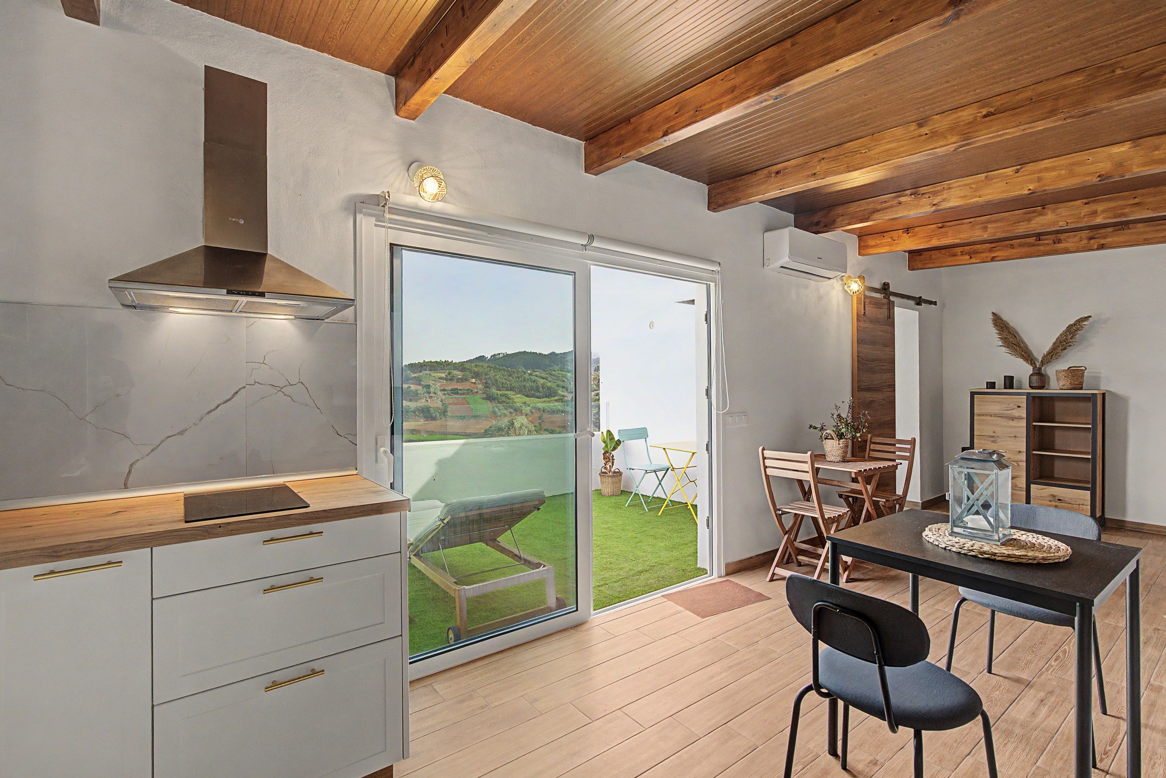 Una cocina moderna con estufa integrada, puerta corredera de vidrio que da a un patio con vistas al campo.