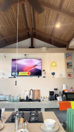 Eine moderne Küche mit Fernseher, Gasherd und diversen Küchengeräten.