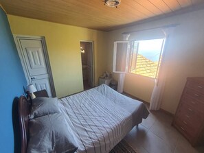 A bedroom with a bed, a dresser, a nightstand, and a window with curtains. - Private room with en-suite and private access (Calheta)