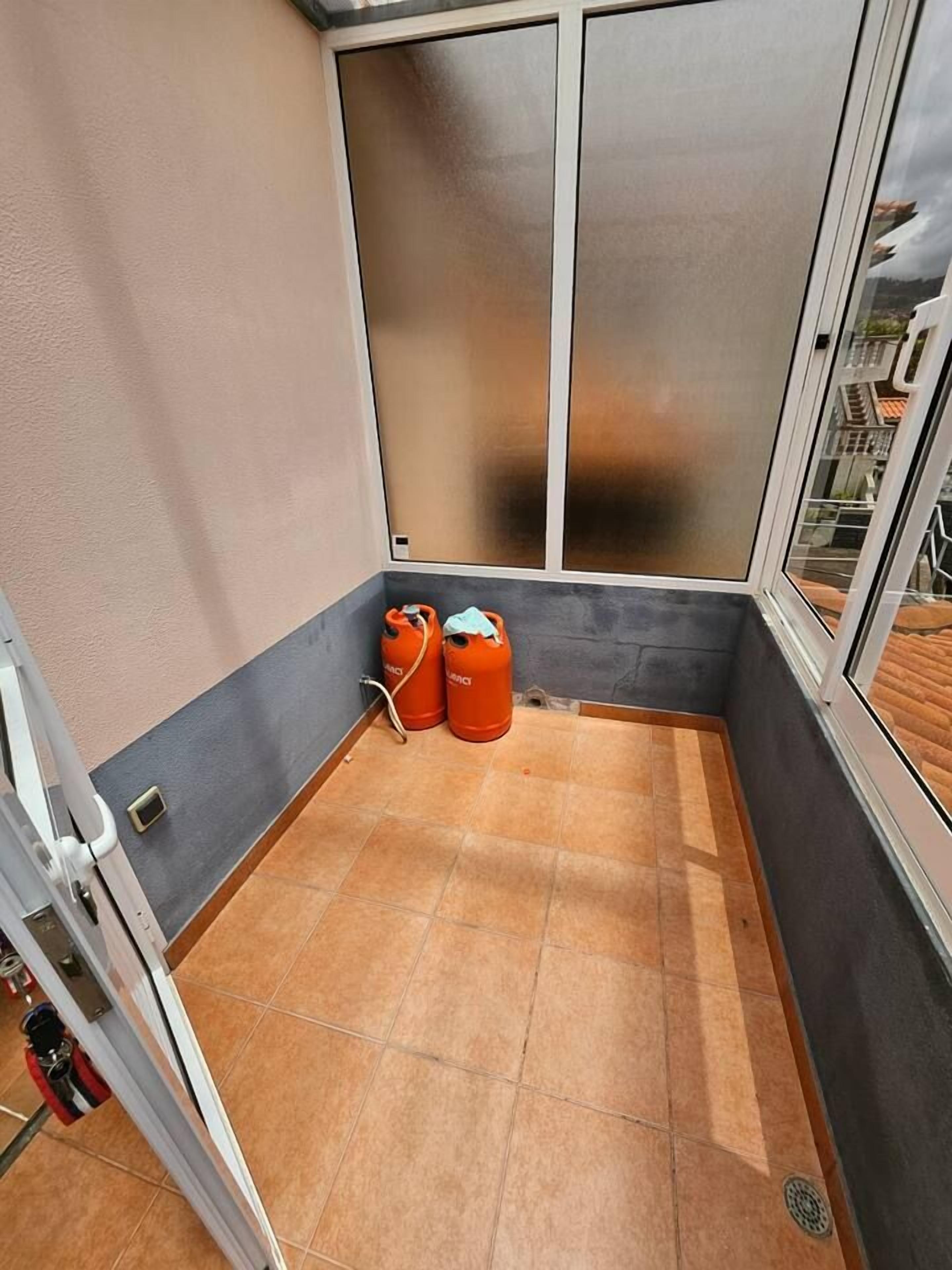 A corner room with a sliding door, a tiled floor, and two orange gas cylinders.