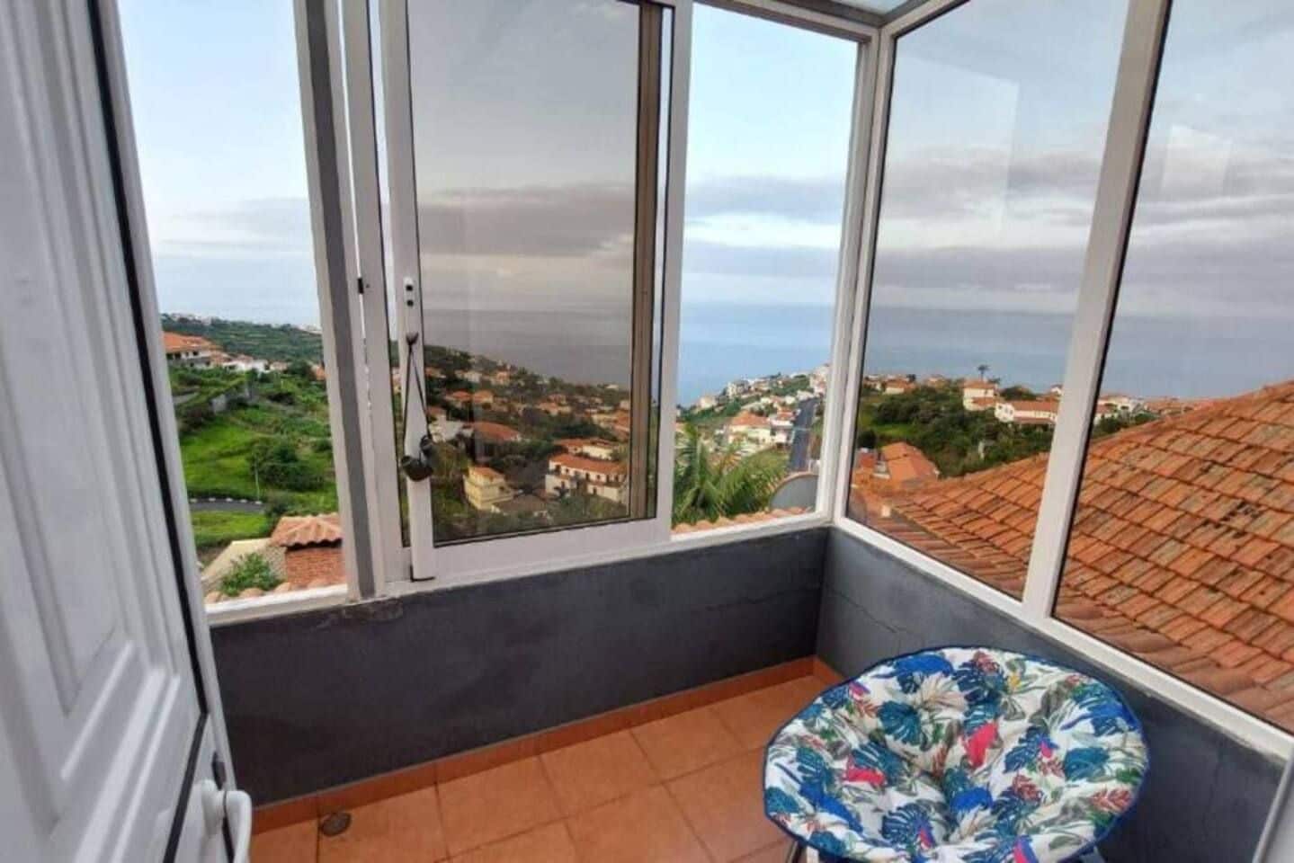 Ein Balkon mit Blick auf eine Küstenstadt, ein Stuhl und eine Tür.
