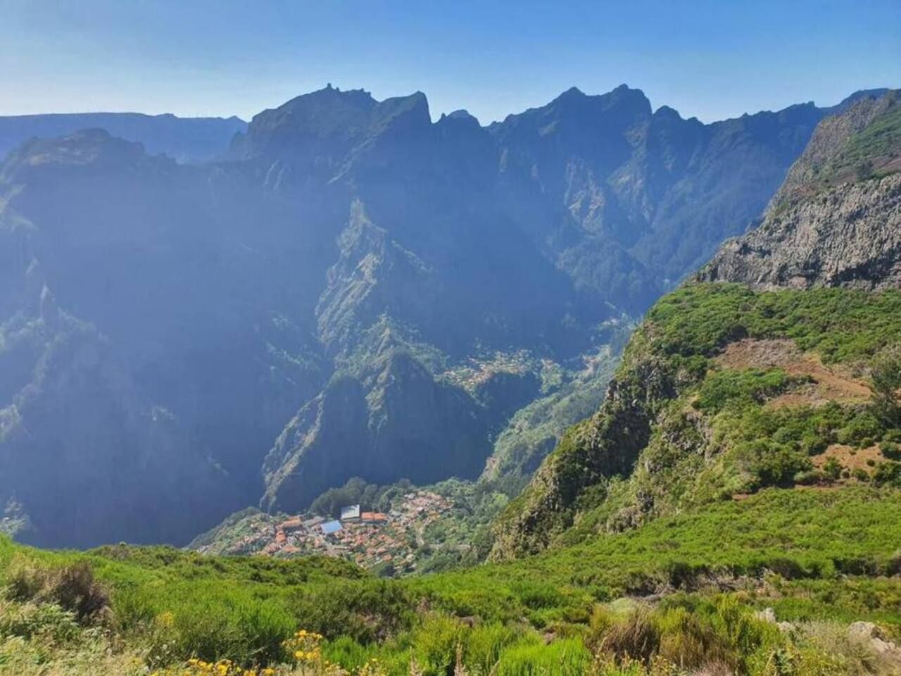 A mountainous landscape with a valley and a small settlement.