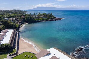 A coastal property with a beach, ocean view, and a mountainous backdrop.