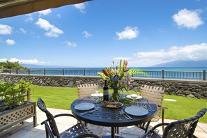 An outdoor dining area with a table set for two, overlooking a scenic ocean view.