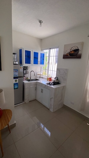 A compact kitchen with white cabinets, a sink, and a window.