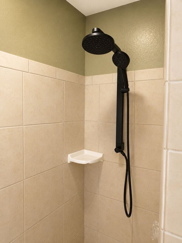 A shower area with a handheld showerhead, a white shelf, and beige tiled walls. - Escape to Tangled Desert Nest- 3B/2B where your lake days & desert sunsets meet! (Lake Havasu City)