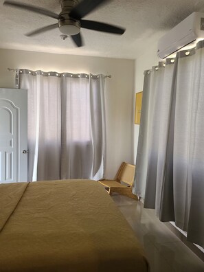 Une chambre à coucher avec un lit, un ventilateur de plafond et des rideaux.