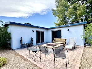 A patio area with a table and chairs, a stone fire pit, and a bench. - Bear Down Arizona- It's Gametime! (Tucson)