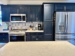 A modern kitchen with dark cabinetry, stainless steel appliances, and a patterned backsplash. - Bear Down Arizona- It's Gametime! (Tucson)