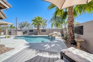 Ein Garten mit Schwimmbad, einer Holzterrasse und einer überdachten Sitzgelegenheit.