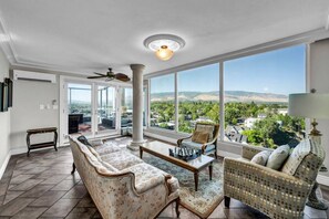 A spacious living room with a large window offering a view of a residential area and hills. - Reno Penthouse | Private Balcony | Mountain Views (Reno)