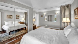 A hotel room with a large bed, a mirror, a door leading to another room, and a view of the outside. - Reno Penthouse | Private Balcony | Mountain Views (Reno)
