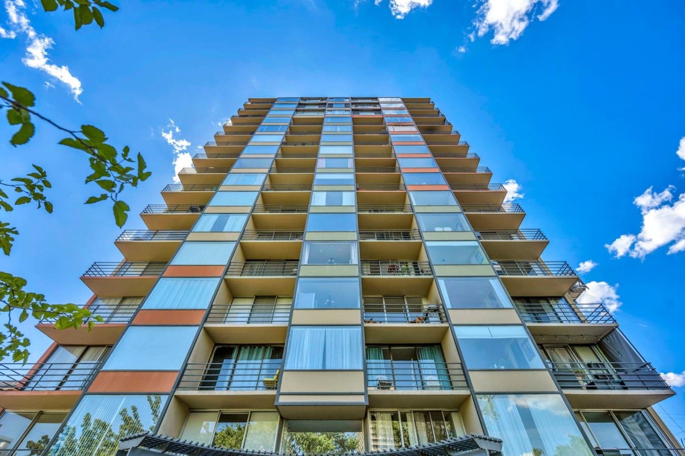 A multi-story building with balconies, large windows, and a clear blue sky.