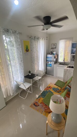 A compact living space with a dining area, kitchenette, and a ceiling fan.