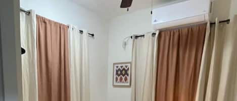 A bedroom with two beds, a ceiling fan, and a nightstand with a lamp.