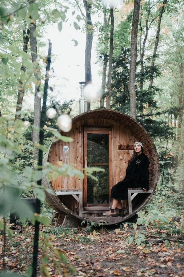 A wooden cabin with a circular structure, a door, and a bench outside.