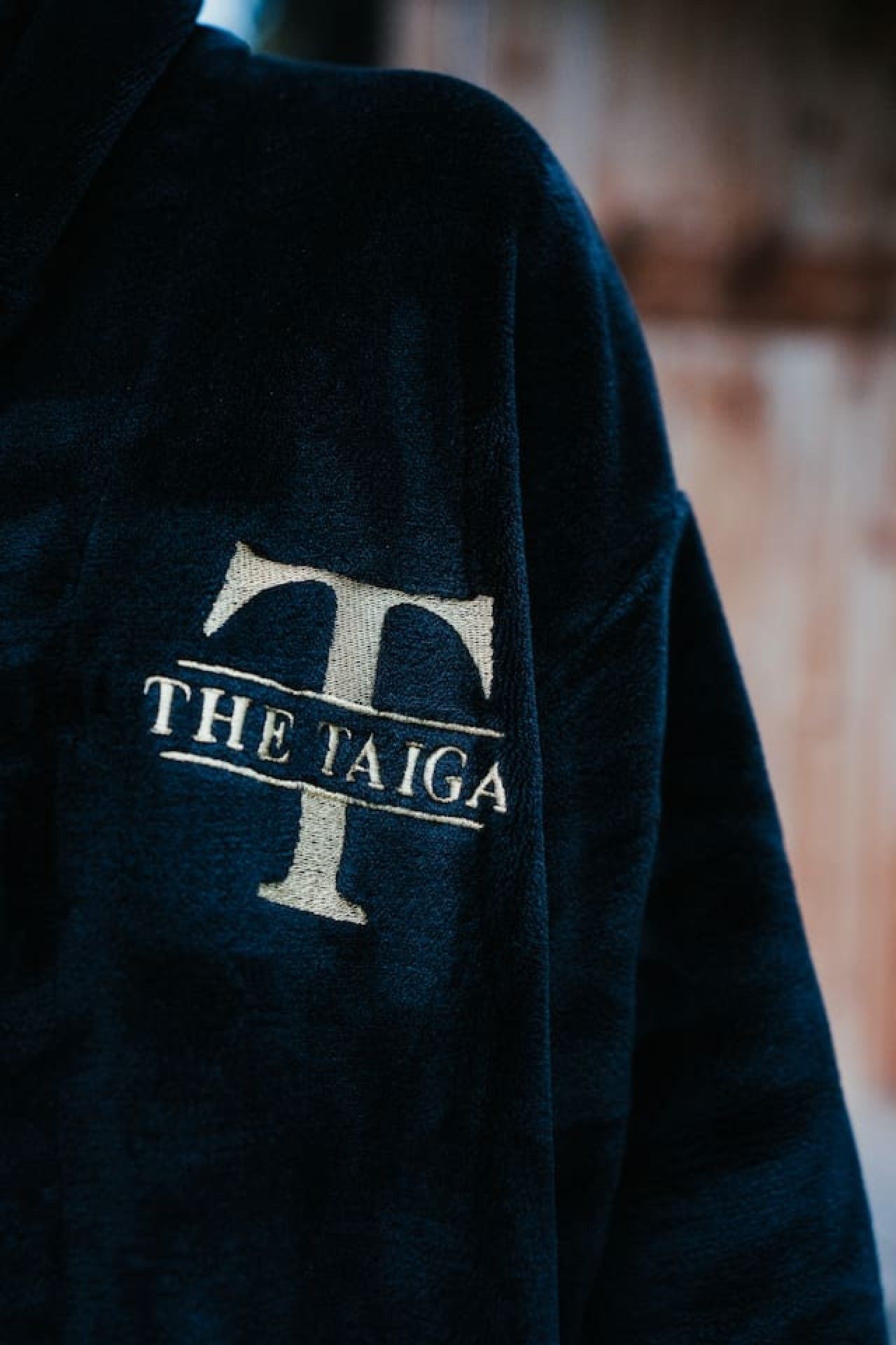 Un vêtement de couleur sombre orné d’un logo et d’une inscription indiquant « THE TAIGA ».