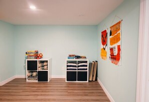A room with light blue walls, wooden flooring, two white shelving units, and two abstract wall hangings. - Animal Sanctuary 10 Acres W/Trails/Sauna/Hottub (East Gwillimbury)