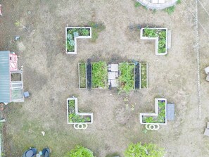 An aerial view of a property with multiple garden beds arranged in a geometric pattern, a small building, and a red-roofed structure. - Animal Sanctuary 10 Acres W/Trails/Sauna/Hottub (East Gwillimbury)