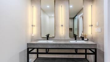 A modern bathroom with two sinks, large mirrors, and wall-mounted lighting.