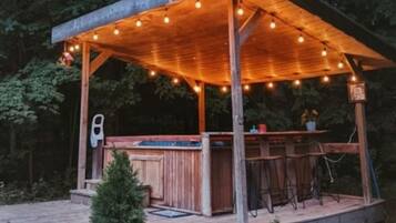 A wooden outdoor bar area with a covered seating section and string lights.