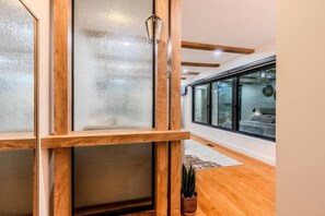 A modern interior with wooden flooring, frosted glass partitions, and a potted plant.