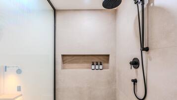 A modern shower area with a built-in shelf for toiletries, a handheld showerhead, and a wall-mounted faucet.