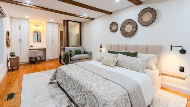 A bedroom with a bed, a desk, a chair, and a mirror.