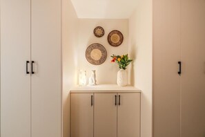 Een kamer met een lichtkleurige garderobe, een plank met decoratieve borden, een vaas met bloemen en een vaas met een object dat op marmer lijkt.