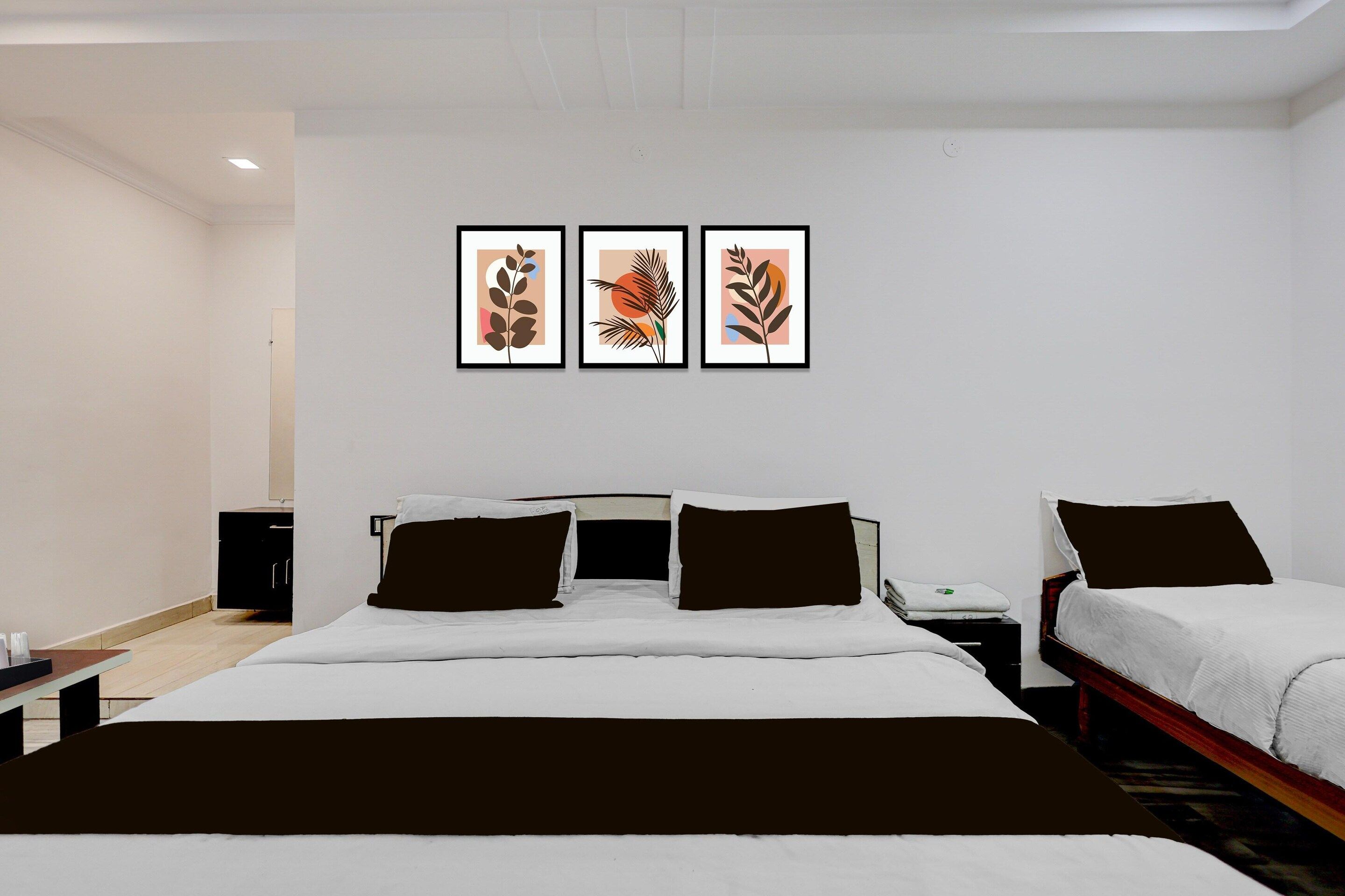 A hotel room with a large bed, two bedside tables, a nightstand, and three framed artworks on the wall.