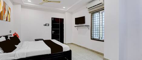 A bedroom with a bed, a ceiling fan, an air conditioning unit, a TV, and a window.